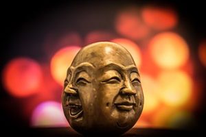 brass figurine depicting two smiling faces of Buddha